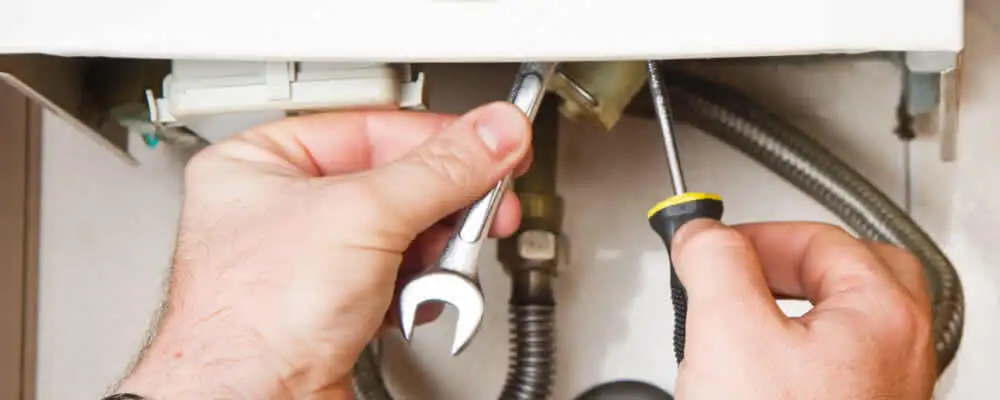 Boiler repair technician tightening pipe fittings and connections in San Jose, CA