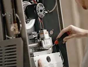 Furnace repair technician inspecting internal components and wiring in San Jose, CA
