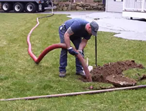 Septic pumping technician servicing a residential septic tank with a vacuum hose in San Jose, CA