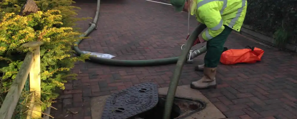 Septic tank cleaning technician servicing a septic tank with a vacuum hose in San Jose, CA